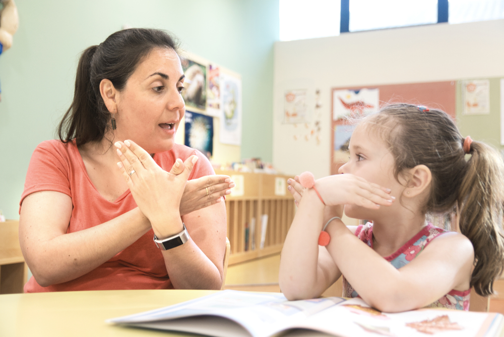 Sign language teacher in a extra tutoring with a deaf child girl